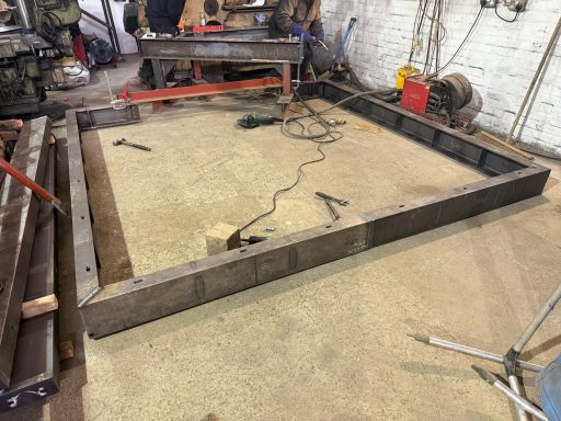 A metal framework in a workshop, with tools and equipment in the background.
